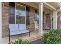Inviting front porch features stone accents, and comfortable seating area with decorative plants at 1018 Tranquil Creek Way, Wake Forest, NC 27587