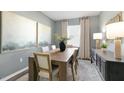 Elegant dining room with a large wooden table, statement artwork, and contemporary lighting at 102 Saddle Mare St, Clayton, NC 27520