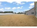 View of a wide backyard featuring dormant grass, a white fence, and a propane tank, bordered by woods in the distance at 303 Bella Sq, Smithfield, NC 27577