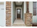 Inviting entryway with stone pillar accents, a wooden front door, and a pathway leading to the home's entrance at 303 Bella Sq, Smithfield, NC 27577