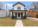 Inviting two-story home with white siding, black trim, and welcoming front porch with brick pillars at 405 N Hyde Park Ave, Durham, NC 27703
