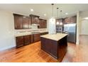 Spacious kitchen with dark wood cabinets, center island, stainless steel appliances, and hardwood floors at 1546 Tinos Overlook Way, Apex, NC 27502
