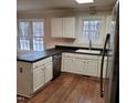 Kitchen features white cabinets, black countertops, stainless dishwasher and wood floor at 266 Sagamore Dr, Louisburg, NC 27549