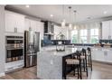 Modern kitchen with stainless steel appliances, an island with bar stools, and white cabinetry and dark backsplash at 810 Hyperion Aly, Wake Forest, NC 27587