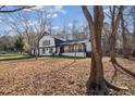 Exterior of home with a white facade, dark trim, complemented by the natural scenery and bare trees at 14115 Allison Dr, Raleigh, NC 27615