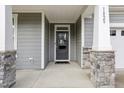 Inviting front porch featuring stone accents, a dark-colored front door, and a covered entryway at 1829 Knights Crest Way, Wake Forest, NC 27587