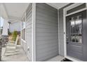 Charming front porch with gray siding, stone accents, a dark front door, and classic white rocking chairs at 1829 Knights Crest Way, Wake Forest, NC 27587