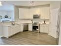 Bright kitchen features white cabinets, stainless steel appliances, light countertops, and wood-look flooring at 2114 Stoney Spring Dr, Raleigh, NC 27610