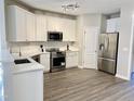 Bright kitchen features white cabinets, stainless steel appliances, light countertops, and wood-look flooring at 2114 Stoney Spring Dr, Raleigh, NC 27610