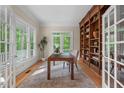 Home office featuring built-in bookshelves, hardwood floors, and french doors leading to the outside at 216 Copper Beech Ct, Chapel Hill, NC 27517