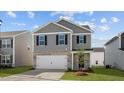 Charming two-story home with gray siding, brick details, an attached garage and front lawn at 258 Palm Dr, Sanford, NC 27332