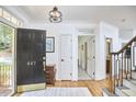 Bright foyer with hardwood floors, staircase, black door with gold numbers, rug, and view to dining area at 407 Crickentree Dr, Cary, NC 27518