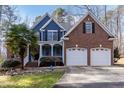 Two-story home with blue siding and brick accents, featuring a two-car garage and landscaped front yard at 4325 New Hope Springs Dr, Hillsborough, NC 27278