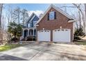 Two-story home with brick accents and a two-car garage, complemented by lush greenery at 4325 New Hope Springs Dr, Hillsborough, NC 27278