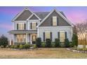 Elegant two-story home with stone accents, black shutters, manicured bushes, and a covered front porch at 58 Atkins Village Ct, Fuquay Varina, NC 27526