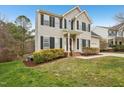 Charming home featuring a landscaped yard, complemented by a red front door and black shutters at 8409 Astwell Ct, Raleigh, NC 27615