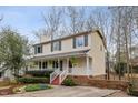Inviting two-story home with covered porch, white railings, red stairs and lush landscaping at 905 Balmoral Dr, Cary, NC 27511