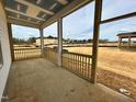 Covered porch with wooden railings overlooks the construction site, seamlessly blending indoor and outdoor living at 104 N Stonemill Trl # Homesite 253, Clayton, NC 27520