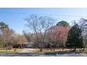 A single-story home with a long driveway is nestled among mature trees and colorful foliage on a sunny day at 1413 Bud Hawkins Rd, Dunn, NC 28334