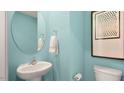 Powder bathroom features include a round mirror, pedestal sink, and stylish decor against teal walls at 240 Holton St, Smithfield, NC 27577
