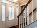 Bright foyer features a decorative glass front door, staircase with wooden handrail, and neutral wall paint at 704 Tranter Dr, Apex, NC 27502