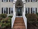 Inviting front entrance features brick steps, white railings, and a stylish black front door at 704 Tranter Dr, Apex, NC 27502