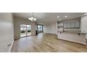 Open living room and kitchen area with light wood floors, granite breakfast bar, and sliding glass patio door at 7727 Weathered Oak Way, Raleigh, NC 27616