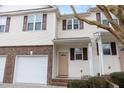 Two-story townhome with attached garage, brick facade, and light yellow vinyl siding at 4618 Pooh Corner Dr, Raleigh, NC 27616