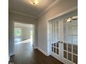 Hallway view featuring hardwood floors, white trim, and French doors leading to other rooms at 4881 Grosbeak Ct, Mebane, NC 27302