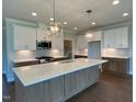 A modern kitchen with an island, white cabinets, stainless steel appliances, and pendant lighting at 4881 Grosbeak Ct, Mebane, NC 27302