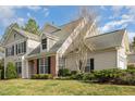 View of the exterior of the home featuring brick accents, mature landscaping, and a manicured lawn at 9510 Dellbrook Ct, Raleigh, NC 27617