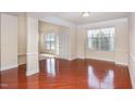 Sunlit living room featuring gleaming hardwood floors, large windows, and neutral decor at 9510 Dellbrook Ct, Raleigh, NC 27617