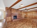 Spacious living room features a brick fireplace, wood paneling, wood beams and hardwood floors at 9550 Silk Hope Liberty Rd, Siler City, NC 27344
