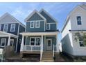 Inviting two-story home with light blue siding, white trim, and a charming front porch with classic white railings at 1905 Plott Balsam Dr, Wendell, NC 27591