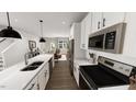 Bright, open kitchen with white cabinets, stainless steel appliances, and hardwood flooring at 1907 Plott Balsam Dr, Wendell, NC 27591