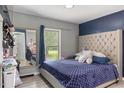 Cozy bedroom with a tufted headboard, blue bedding, and a window offering natural light at 2728 Old Milburnie Rd Rd, Raleigh, NC 27604