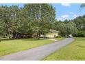 A long driveway and yard leading to a charming yellow house, surrounded by lush greenery and mature trees at 2728 Old Milburnie Rd Rd, Raleigh, NC 27604