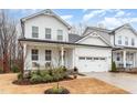 Charming two-story home with white siding, a covered porch, and a two-car garage, creating a welcoming curb appeal at 349 Shadow Falls Dr, Wendell, NC 27591