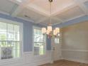 Dining room featuring coffered ceilings, wainscotting, and a modern light fixture with windows providing natural light at 3529 Bailey Lk Dr, Fuquay Varina, NC 27526