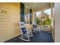 Inviting front porch with rocking chairs, dark blue floor, wood railings and a glimpse of the front yard at 513 E Franklin St, Chapel Hill, NC 27514