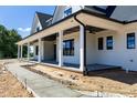 A covered front porch that offers a relaxing outdoor space, framed by elegant white columns and black trim at 6509 Zebulon Rd, Wake Forest, NC 27587