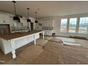 Unfinished kitchen featuring white cabinets, a large island, and natural light from the backyard windows at 79 Willow Cameron Way, Angier, NC 27501