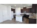 Contemporary kitchen with dark wood cabinets, white island, and stainless steel appliances at 937 Emmer St, Rolesville, NC 27571