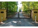 Elegant gated entrance to a horse property with a long, winding driveway through lush greenery and mature trees at 1018 Terrell Woods Ln, Chapel Hill, NC 27516