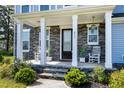 Inviting front porch with stone pillars, rocking chairs, and well-manicured landscaping at 213 W Weatherford Dr, Angier, NC 27501