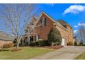 Brick home showcasing the attached garage, manicured lawn, and elegant architecture details on a sunny day at 4270 Aviemore Run, Burlington, NC 27215
