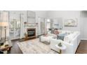 Spacious living room featuring a fireplace, large windows, hardwood floors, and elegant white furniture at 4270 Aviemore Run, Burlington, NC 27215