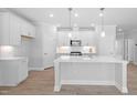 Bright, white kitchen featuring a central island, stainless steel appliances and modern pendant lighting at 44 Belmont Stakes Ln, Wendell, NC 27591