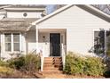 A close up of the home's entrance, featuring a black front door, brick steps, and white porch railing at 475 Beechmast, Pittsboro, NC 27312