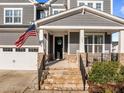 Inviting front porch with stone steps, black railings, and an American flag at 516 Ivy Arbor Way, Holly Springs, NC 27540